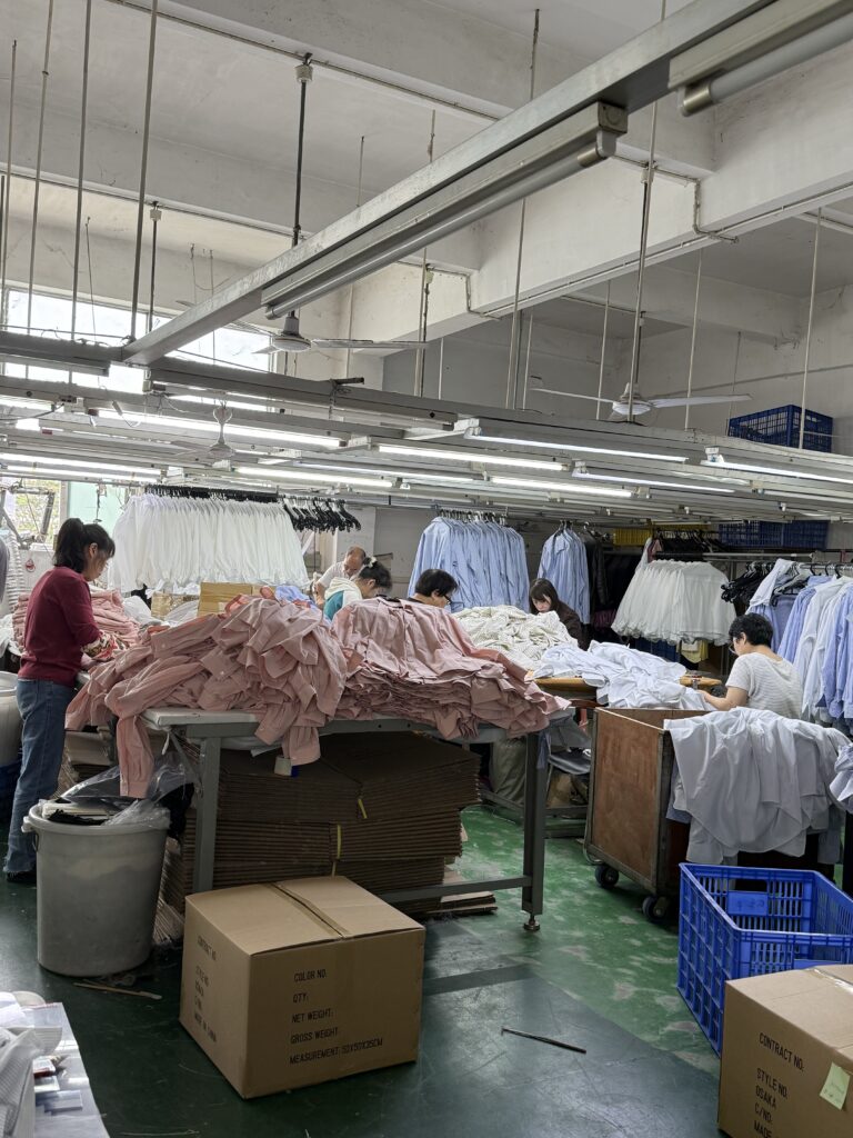 Professional garment production workshop at Tetramade Shenzhen showing skilled workers and high-volume order processing.